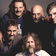 Group of 5 smiling men bunched in close together.