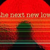 A round circle of red glass with silhouette of person outside against black background.