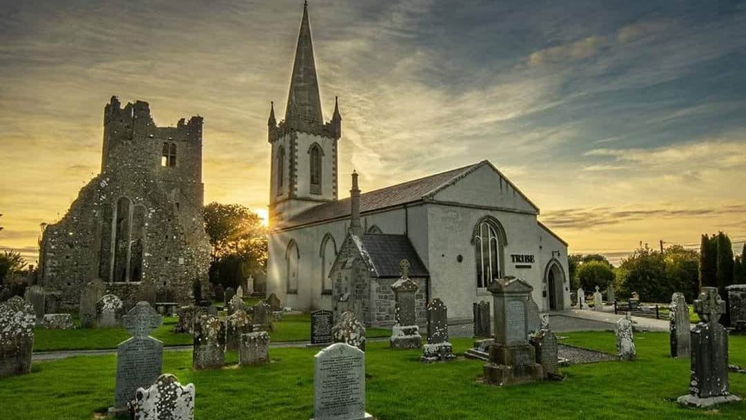 Graveyard in front of a church style building at sunset