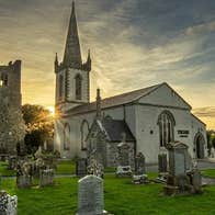 Graveyard in front of a church style building at sunset