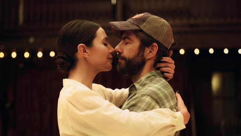 A man and woman are nose to nose in an embrace