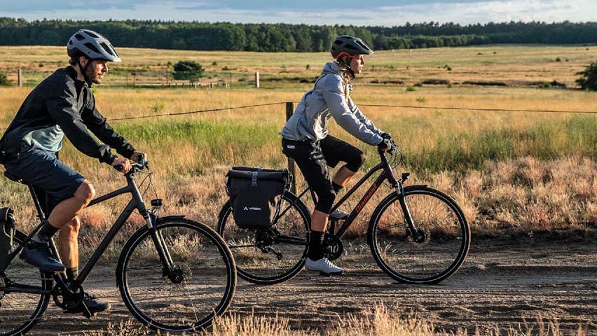 A man and woman cycling along a trackway in an open field