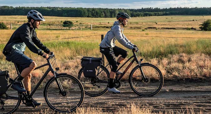 A man and woman cycling along a trackway in an open field