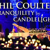 A man in the background playing a pale coloured grand piano with blurry lit candles in the foreground.