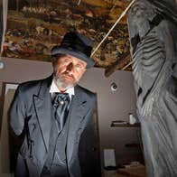 Waterford Treasures - Irish Wake Museum guide in a top hat next to a stone skeleton carving