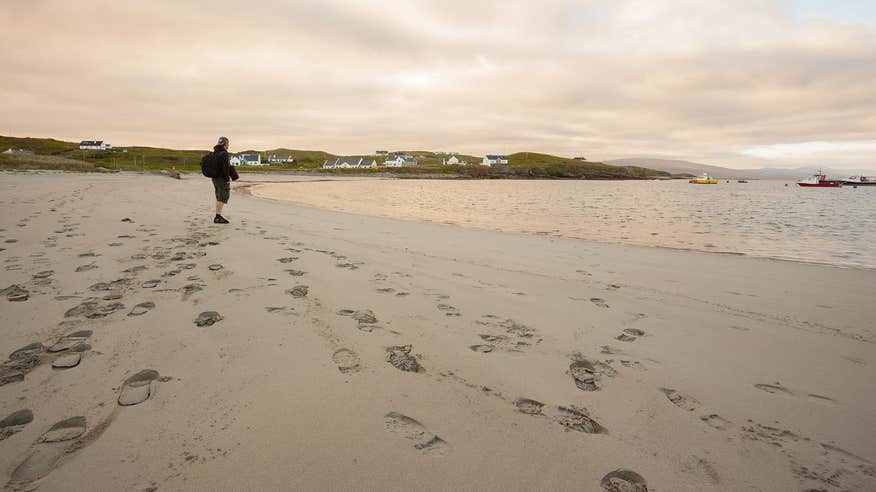 A man with a backpack walking along the beach and staring out to sea at Clare Island Beach, Mayo