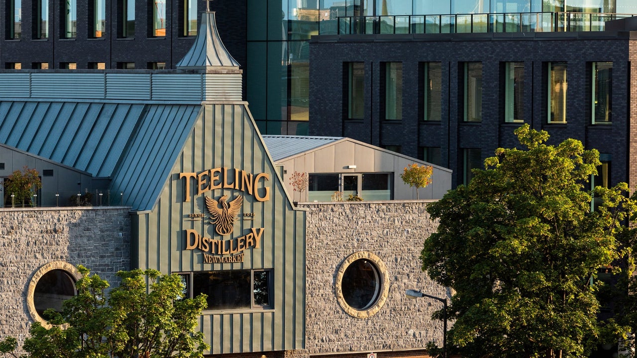 Outside image of a distillery with two stone walls on either side of a green front