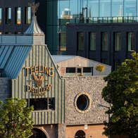 Outside image of a distillery with two stone walls on either side of a green front