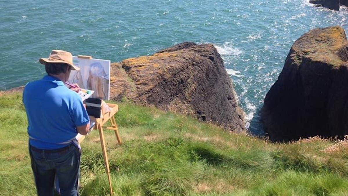 An artist painting on a cliff top