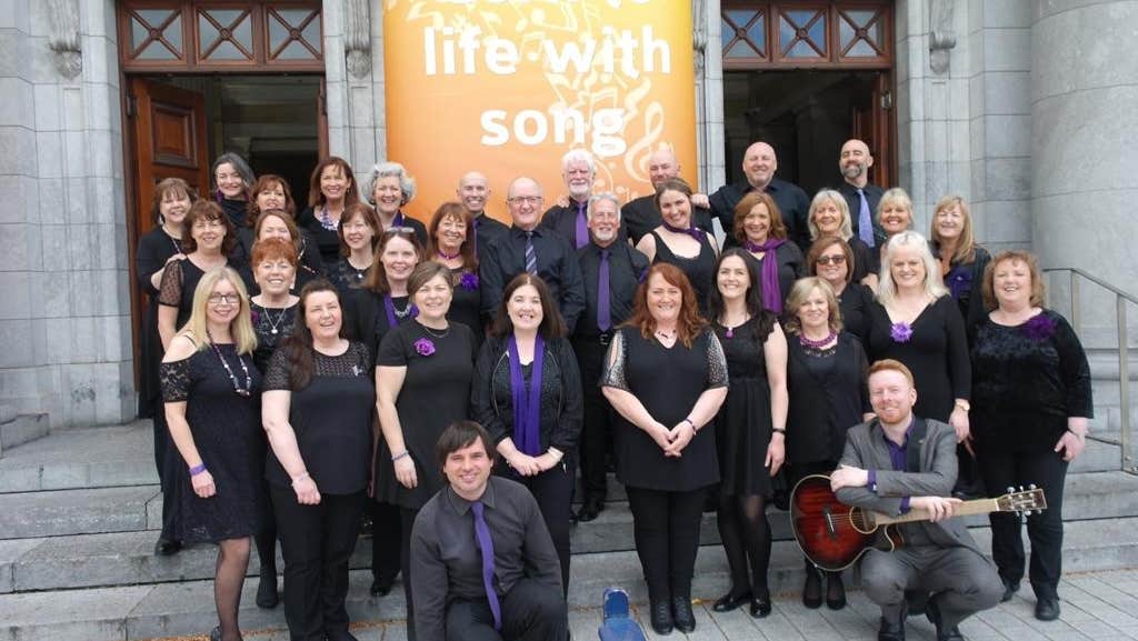 A group of smiling people dressed in black on some stone steps