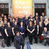 A group of smiling people dressed in black on some stone steps