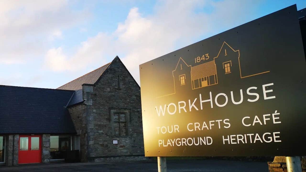 An old workhouse building with a business sign in the foreground