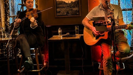 Live traditional Irish music performance featuring a fiddle player and guitarist in a cosy pub setting