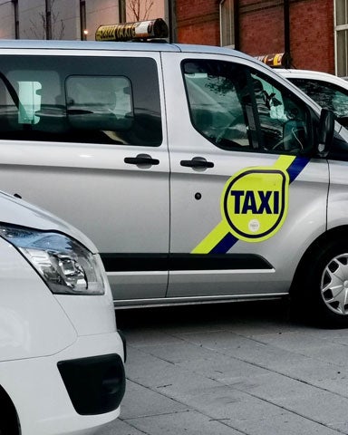 Three taxi minivans parked at an angle