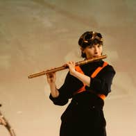 A woman dressed in black playing a wooden coloured flute