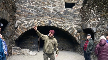 A guide sharing the history of an impressive stone castle interior