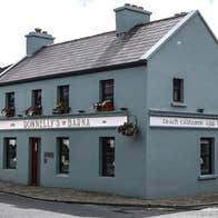 The exterior of a two storey pub and restaurant on a corner painted a mainly grey colour