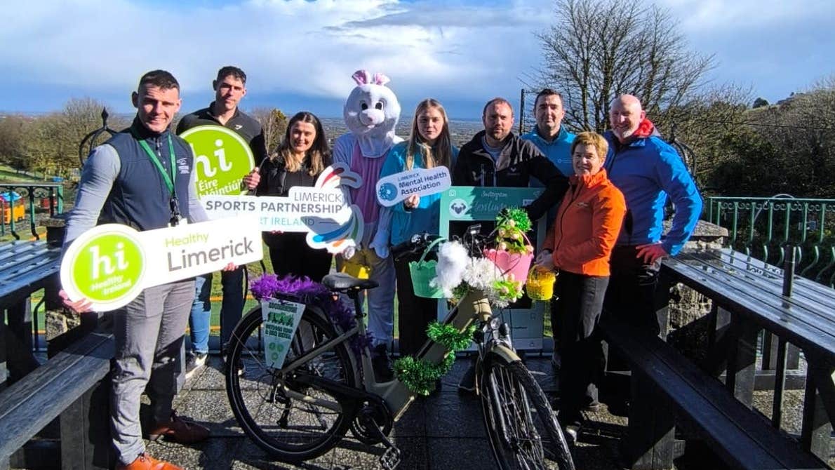 A group of people outdoors with a bike, a person dressed in white bunny costume and some holding hashtag signs.