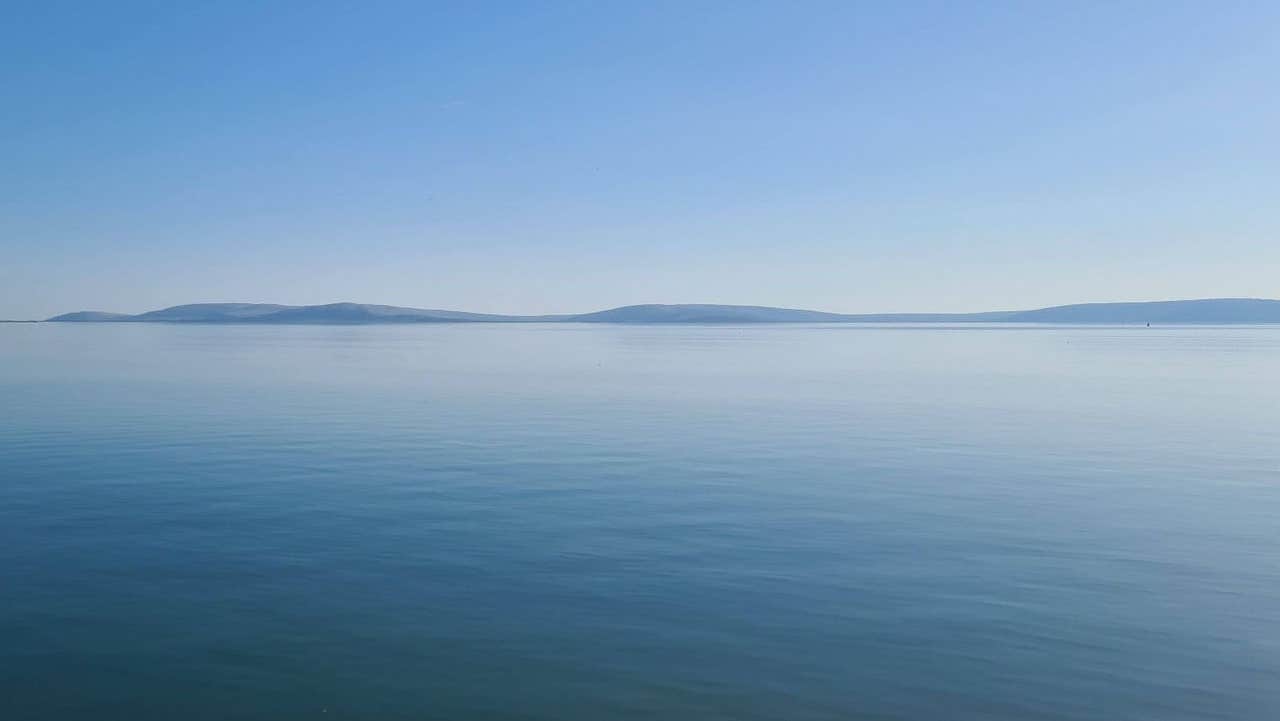 Calm blue sea with distant low hills on the horizon