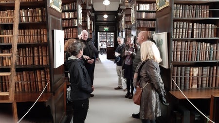 Visitors gather among the towering oak bookcases of Marsh's Library, Dublin's oldest public library, filled with centuries-old volumes — a fitting stop for tracing the roots of Irish gothic literature.