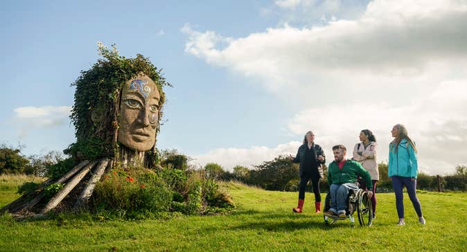 Three people receiving a tour of Hill of Uisneach in County Westmeath.