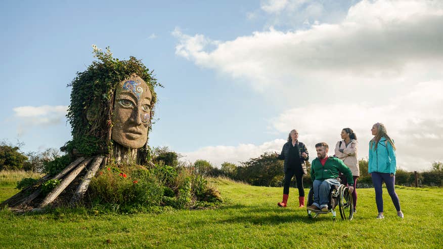 Three people receiving a tour of Hill of Uisneach in County Westmeath.