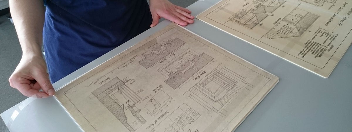 A person looking at some old building drawing plans