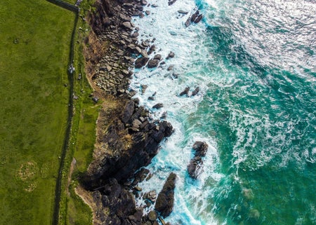 An aerial view of waves along a rocky coastline