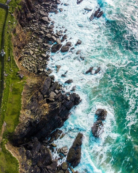 An aerial view of waves along a rocky coastline
