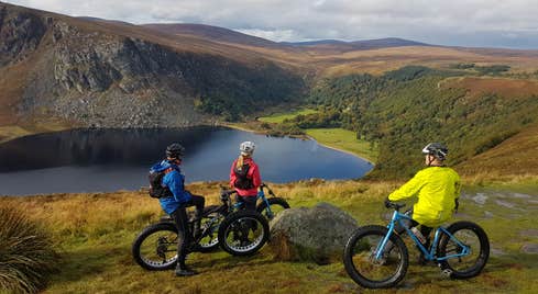 Three people on mountain bikes pausing to gaze at majestic Lough Tay, Wicklow