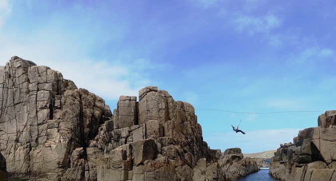 Zip lining between rocks over the sea