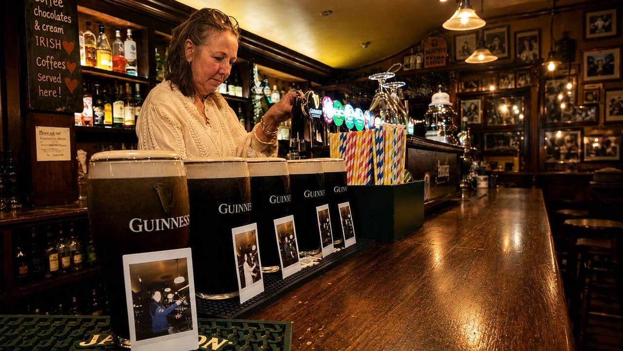 Pints of Guinness lined up on a bar each paired with a polaroid and a bar person pouring another one