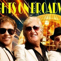 3 smiling men in white suits and dark shirts, all wearing sunglasses with gold, mosaic disco ball in background.