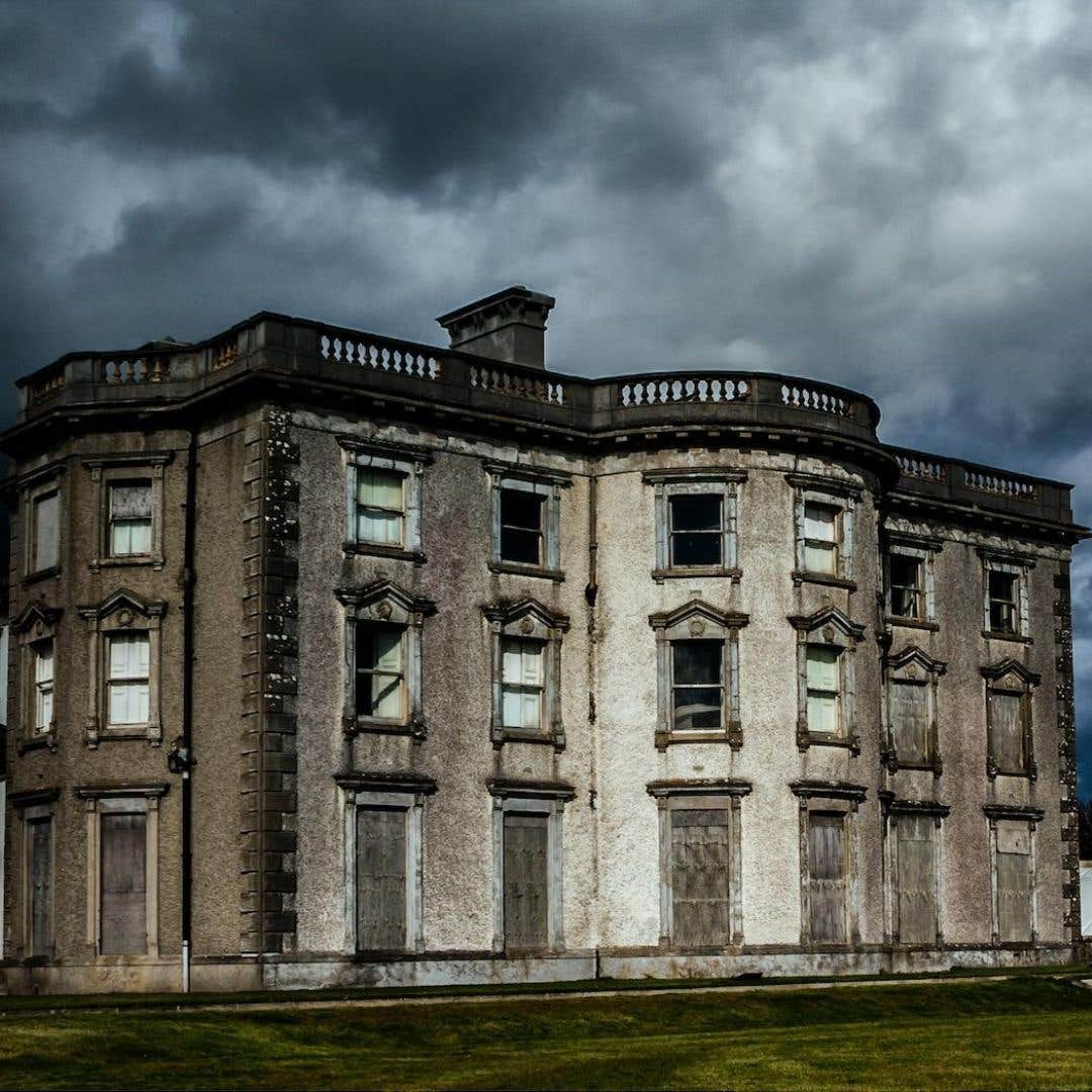 Exterior facade of Loftus Hall in Wexford with storm clouds behind it.