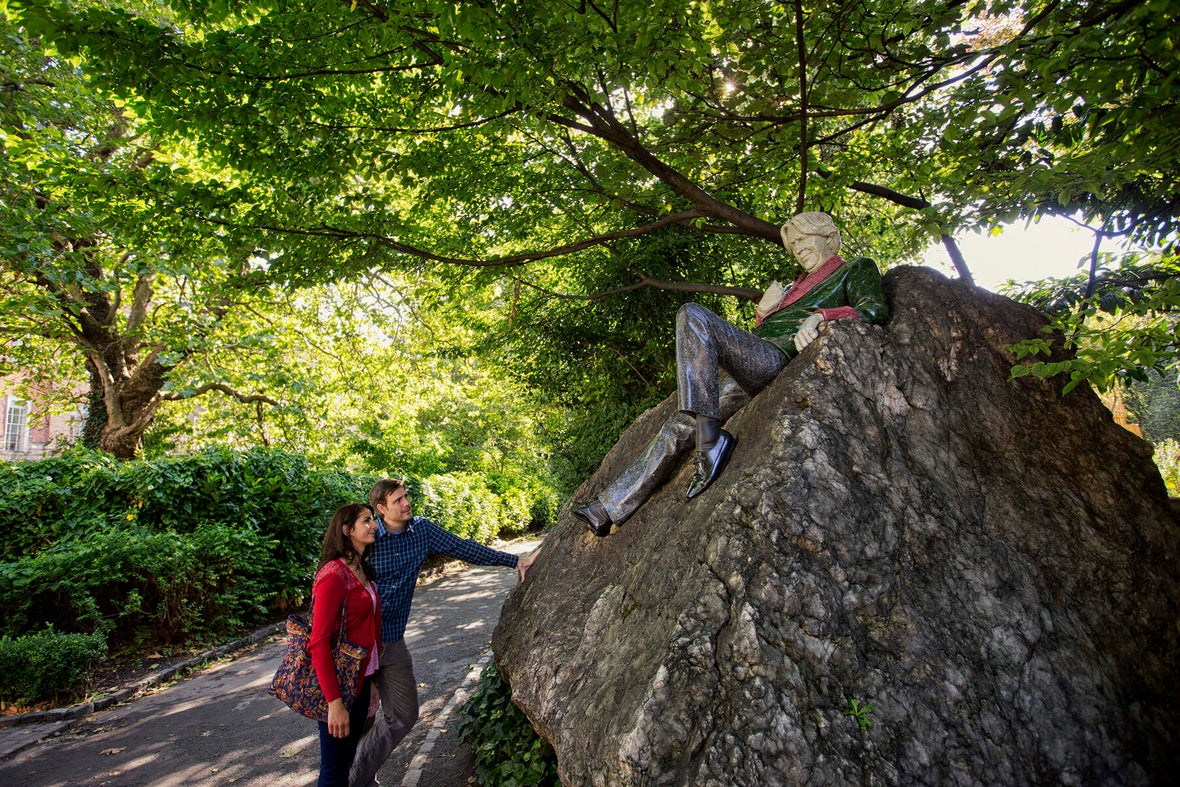 Two people looking at the Oscar Wilde statue in Merrion Square.