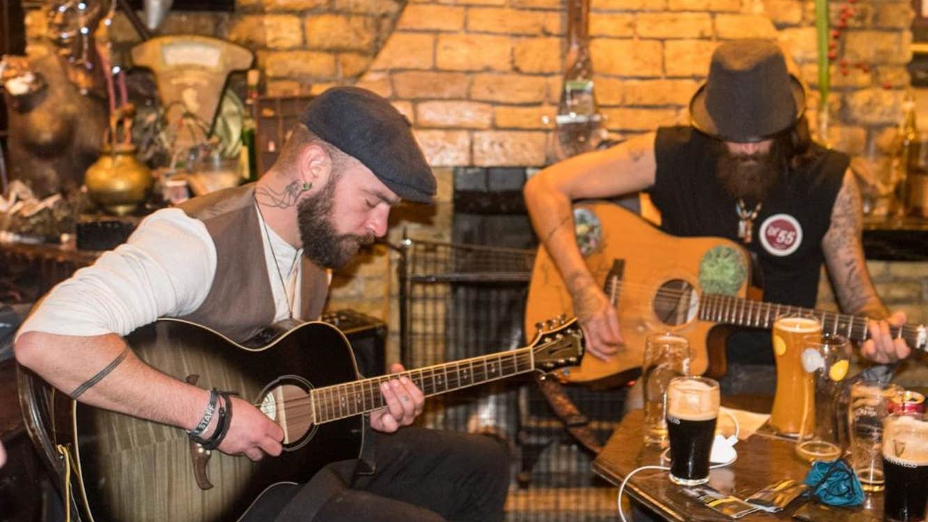 Two musicians playing the guitar at a table in the pub