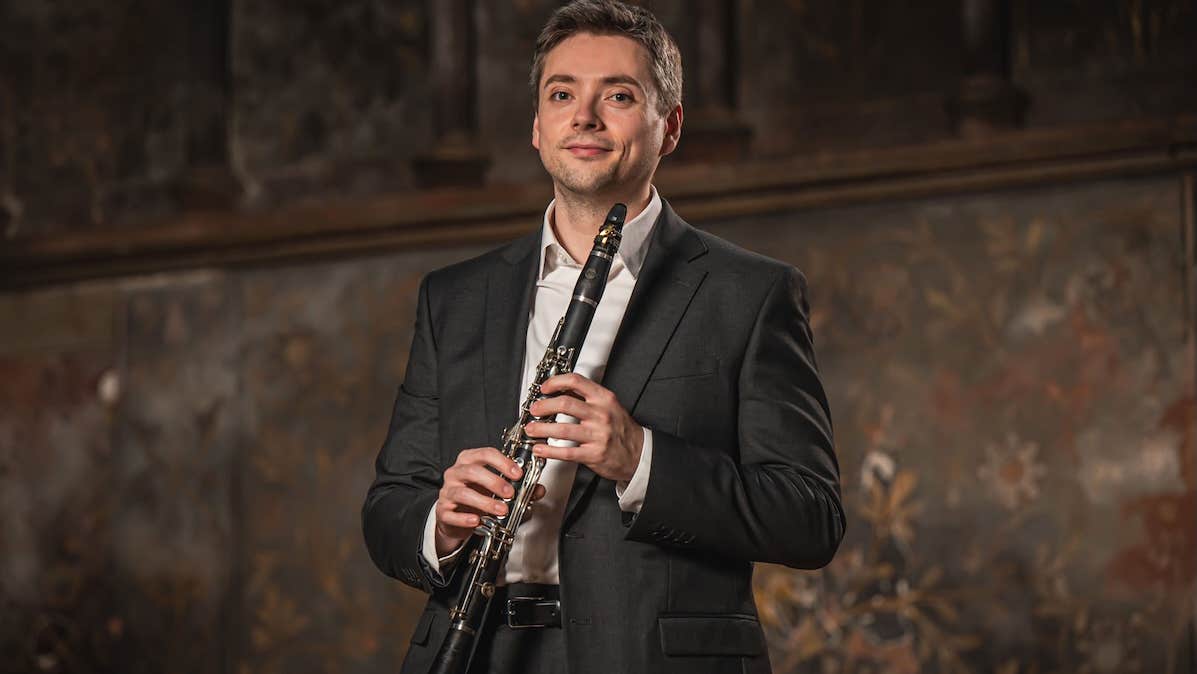 A slightly smiling man holding a clarinet