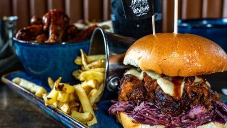 Burger and chips served with wings on the side at Hogs and Heifers