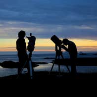 Two people looking up at the sky through telescopes in Dark Sky Park, Kerry