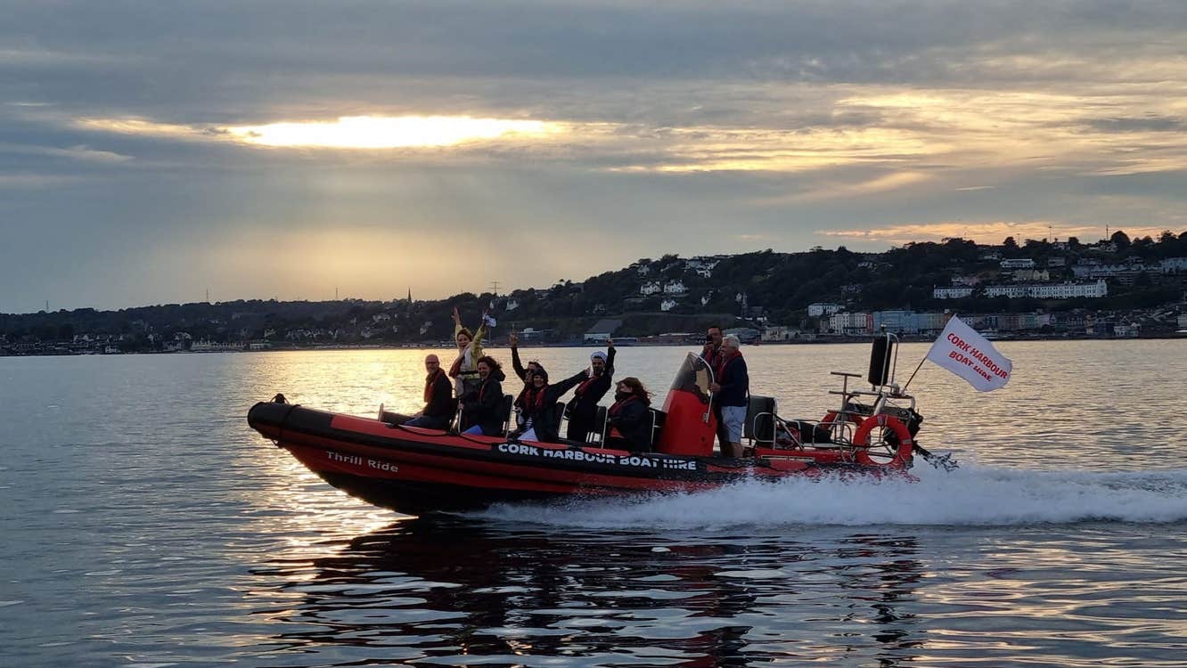 Group on a red and black boat on the water at sunset