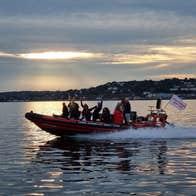 Group on a red and black boat on the water at sunset
