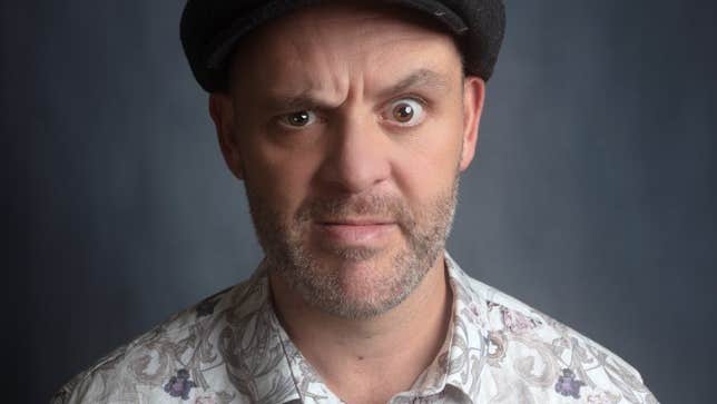 A confused looking man wearing a flat cap and patterned shirt.