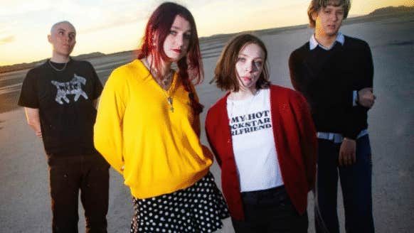Group of 4 people outdoors with water in the background.