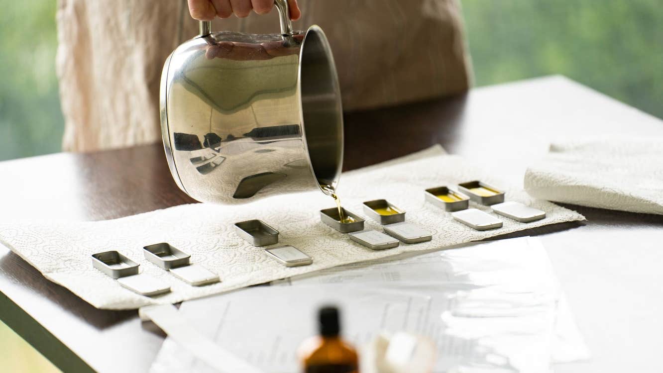 A person pouring liquid into small moulds