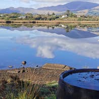 A woman relaxes in a seaweed bath looking out over a lake