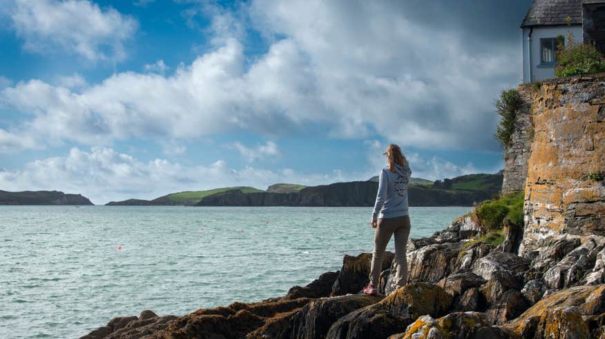 A woman looking out at the still waters and blue skies from Castletownshend Harbour