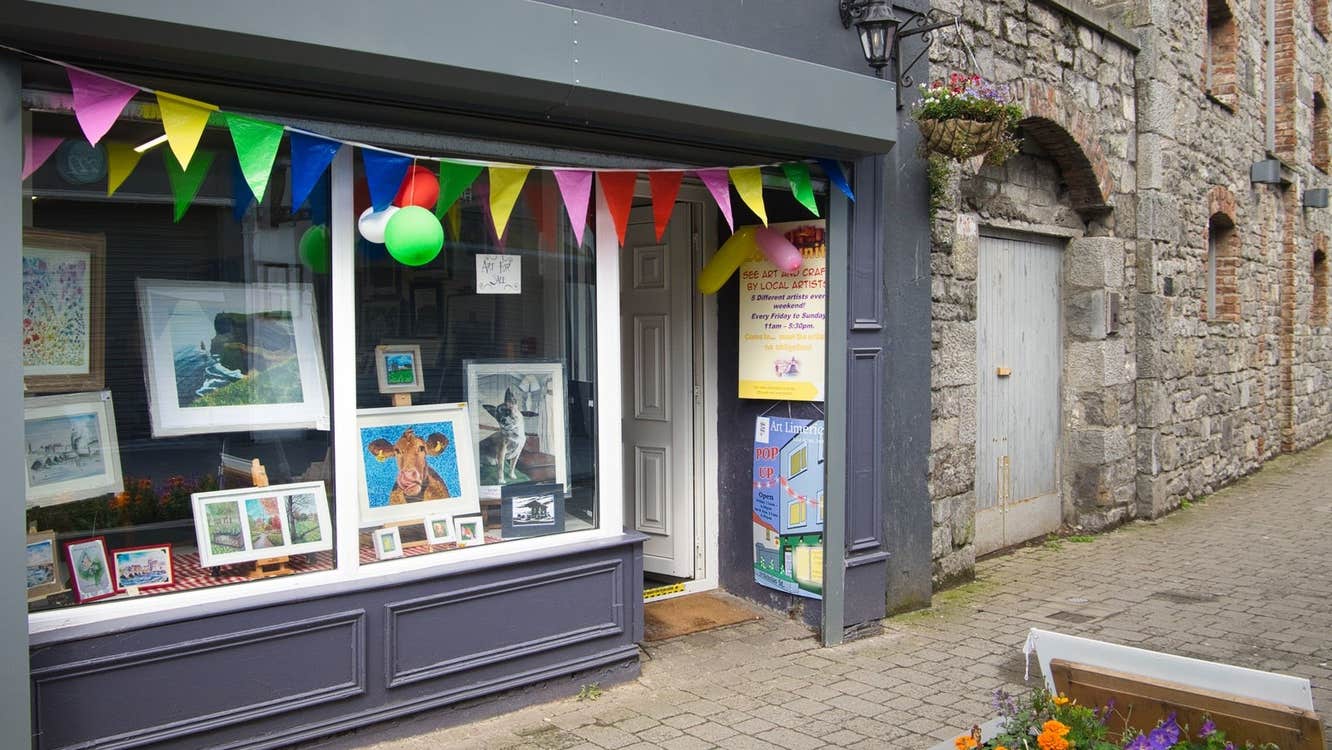 The exterior of a shopfront displaying paintings with bunting and balloons along the top