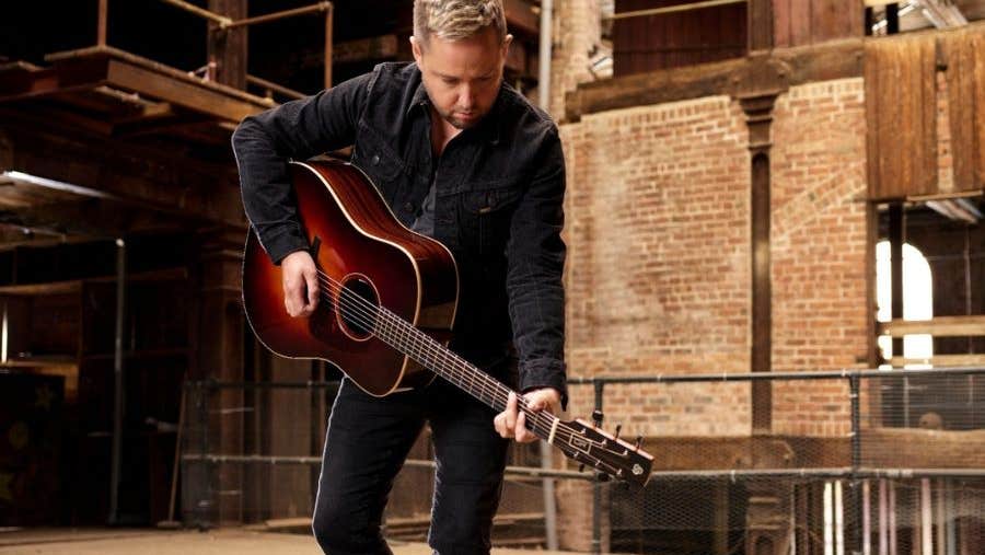 A man playing a guitar looking downwards