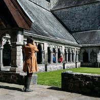 People standing beside grass outside an old stone building