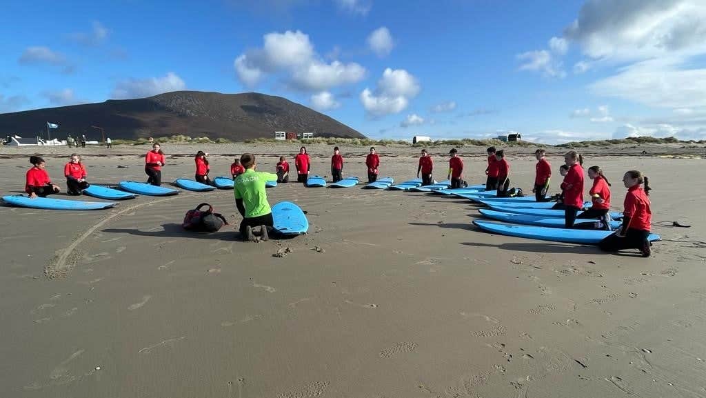 A group of girls with surf board on a beach in a semi circle
